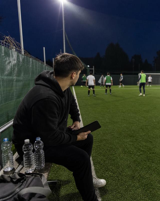 Un organizzatore a bordo campo con il tablet in mano, mentre le squadre giocano sotto i riflettori